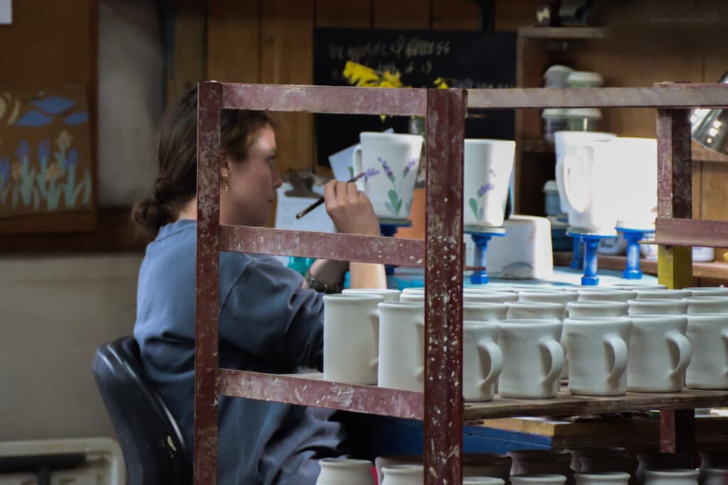 Artist painting lavender pattern on mugs