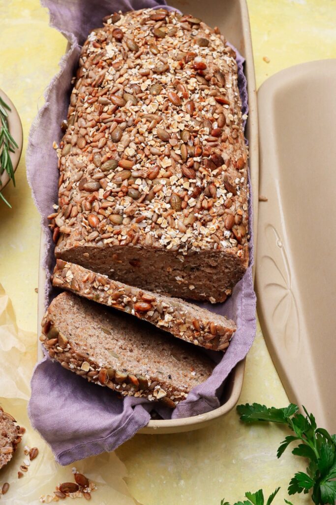 Fresh whole grain bread in covered bread pan.